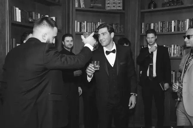 Groom sharing a toast with his groomsmen in the Villa de Amore library