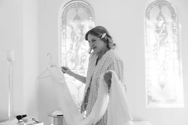 Bride preparing her wedding dress by the arched windows at Villa de Amore