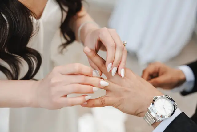 Bride placing a wedding ring on groom's finger during Grace & Oscar's ceremony.