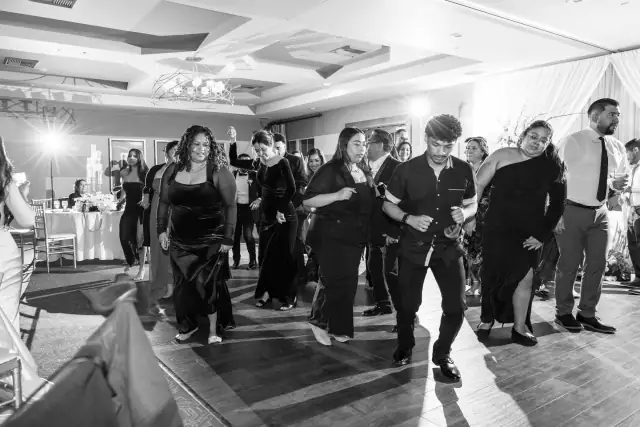 Guests dancing together on the dance floor at a wedding reception indoor venue.