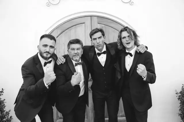 Groom posing with three groomsmen outside Villa de Amore